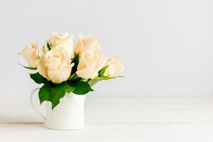 Romantic bouquet of pastel cream roses in a jar on a white background. photo