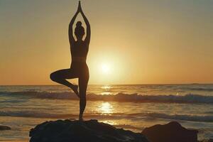 Silhouette of young woman practicing yoga at coastline beach. photo