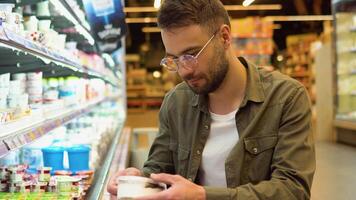 un' uomo shopping latteria Prodotto nel drogheria negozio. lato Visualizza di bello uomo acquisto ghiaccio crema video