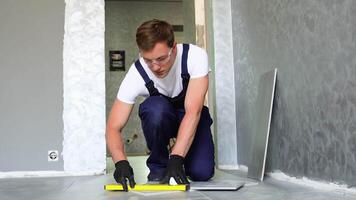 Laying ceramic floor tiles. Worker marking tile to be cut video