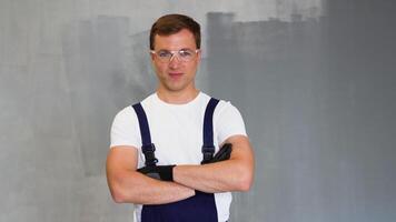 positivo joven reparador en uniforme en pie dentro Departamento y mirando a cámara video