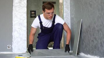 Flooring and tiling. Professional tiler placing floor tiles on adhesive surface on kitchen video