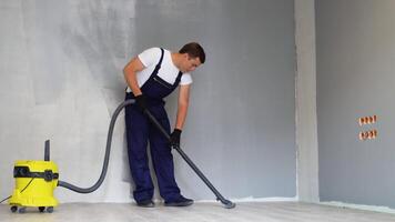 profissional limpeza depois de renovação dentro a sala. uma homem aspiradores a chão. limpeza depois de reparar ou renovação video