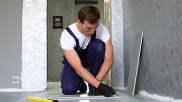 Laying ceramic floor tiles. Worker marking tile to be cut video