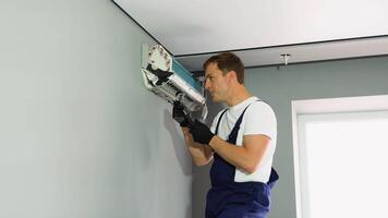 Technician man worker repairing and installs air conditioner on grey wall video