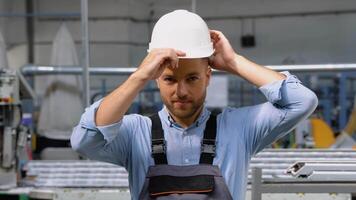 Portrait of the manual man worker in uniform puts on a helmet and looking to the camera video