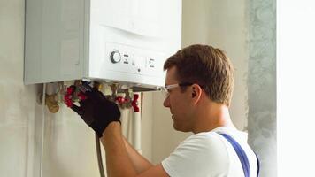 Serious technician setting the new gas boiler for hot water and heating video