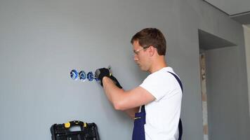 Professional electrician technician installing a wall socket in a new house. Electrician mounting wiring for electric sockets video