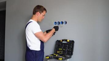 Close up of man installing electrical outlet in wall in room of house. Man doing electrics video