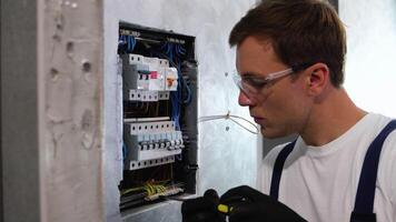 professionell elektriker uppsättningar upp elektricitet i de lägenhet. elektriker reparation elektrisk låda och använder sig av skruvmejsel i korridor video