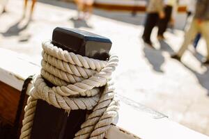 Close-up of old rope on a sailboat deck. Blurred marina on a background. photo