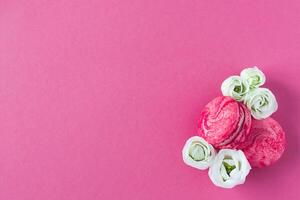 Composition of two pink French macarons and white flowers. Flat lay, place for text. photo