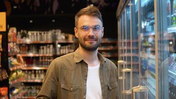 Portrait of a funny buyer at supermarket. Man choosing the right product in a supermarket video