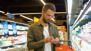 uomo scrittura nel il suo bloc notes nel corridoio a supermercato. un' uomo fa Appunti nel il shopping elenco video