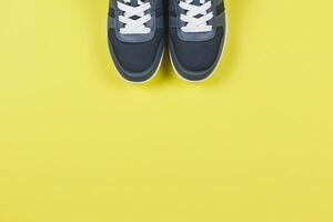 Grey sneakers on the yellow background. Concept for healthy lifestyle and everyday training. photo