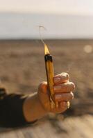 de fumar aromático palo santo palo para meditación en un mano a puesta de sol. foto