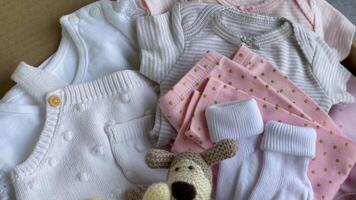 Baby and child clothes and knitted toys in carton box. video