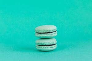 Two French macarons on a turquoise background. Mint macarons. photo