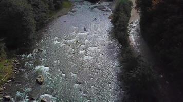 Four sportsmans in blue inflatable canoes are rafting down a mountain river. Aerial view video