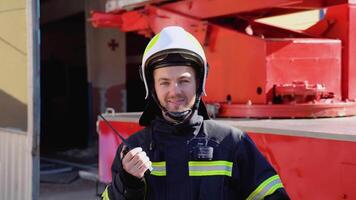 porträtt av Lycklig brandman med walkie talkie nära brand motor. brandman porträtt på plikt video