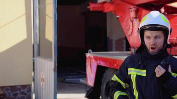 Brave firefighter man talking to walkie talkie with fire truck in background video