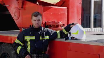 Portrait of fireman with helmet near fire engine. Firefighter portrait on duty video