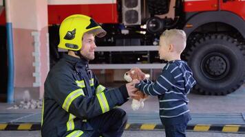 Little boy with firefighter in protective uniform in fire station video
