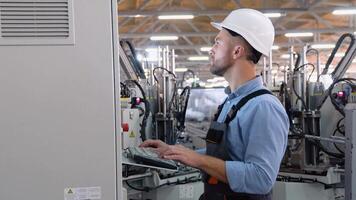 Operator of machine. Industrial worker wearing safety uniform and helmet indoors in factory video