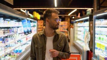 portrait de souriant homme en marchant dans rayon avec le sien trolle à supermarché video