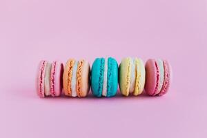 Tasty french macarons on a pink pastel background. photo