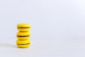 Three yellow french macarons on a wooden table. Banana macarons with chocolate cream. photo