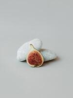 Ripe fig with stones on a grey background. Minimal concept. photo