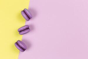 Three french macarons on a yellow and purple background. Place for text. photo