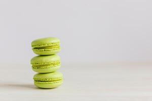 Three light green french macarons on a wooden table. Pistachio macarons. photo