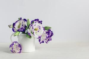 Romantic bouquet of white and purple colored Eustoma flowers in a jar on a white background. photo