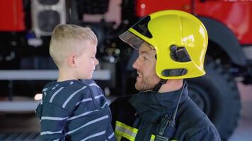 porträtt av brandman med söt pojke på vapen. begrepp av sparande liv, brand säkerhet video