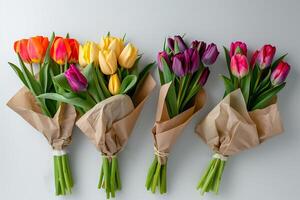 Beautiful bouquets of multicolored tulips wrapped in a craft paper on a grey background. photo