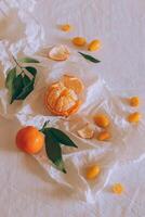 Fresh juicy citrus fruits with green leaves on white craft paper. photo