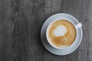 Cup of coffee with latte art on wooden background. Place for text. photo