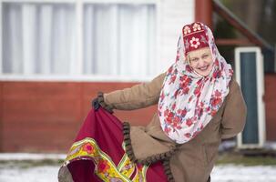 Russian elderly woman in traditional clothes and headdress kokoshnik poses. photo