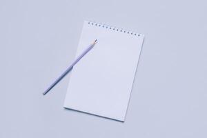 Notebook with blank page and pencil on light purple background. photo