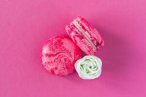 Two pink French macarons with white flower. Flat lay, close up. photo