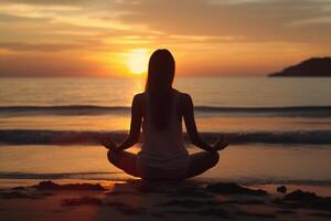 silueta de joven mujer practicando yoga y meditando a línea costera playa. foto