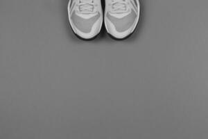 Light grey sneakers on the grey background. Concept for healthy lifestyle and everyday training. photo