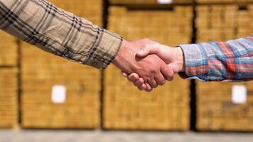 Close-up of a handshake on the background of a composition of boards. Concept of selling wood materials video