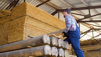 Builder folds wooden timber. Concept - sale of lumber. Builder is considering wood planks video