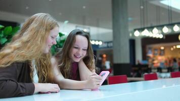 Asian girl and friend ethnic German-Thai taking smart phone selfie in department store. video