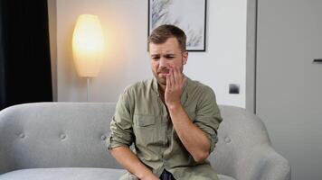 Jeune Beau homme à Accueil émouvant bouche avec main avec douloureux expression car de mal aux dents ou dentaire maladies sur dents. dentiste concept video