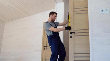 Male carpenter installing interior wood door with level video