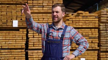 Serious manager in uniform giving commands to workers on timber warehouse. Bearded man gesturing and shouting during working process video